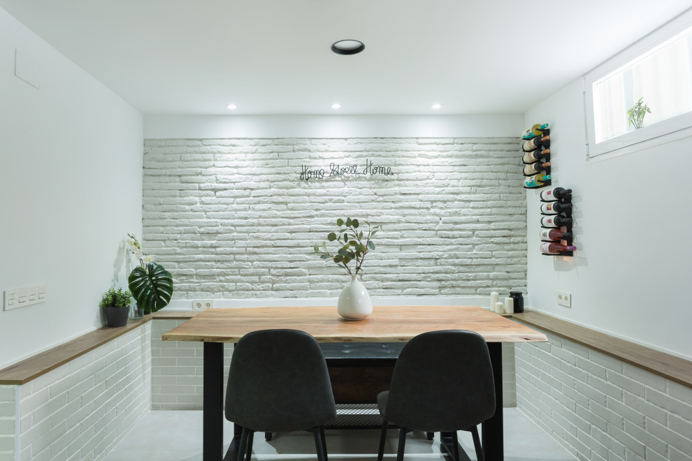 Aménagement d'une petite salle à manger industrielle avec un mur blanc, un sol en carrelage de porcelaine, cheminée suspendue, un sol gris et un mur en parement de brique.