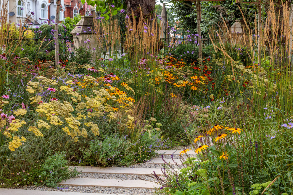 Mittelgroßer Moderner Vorgarten im Sommer mit Blumenbeet, direkter Sonneneinstrahlung, Natursteinplatten und Metallzaun in London