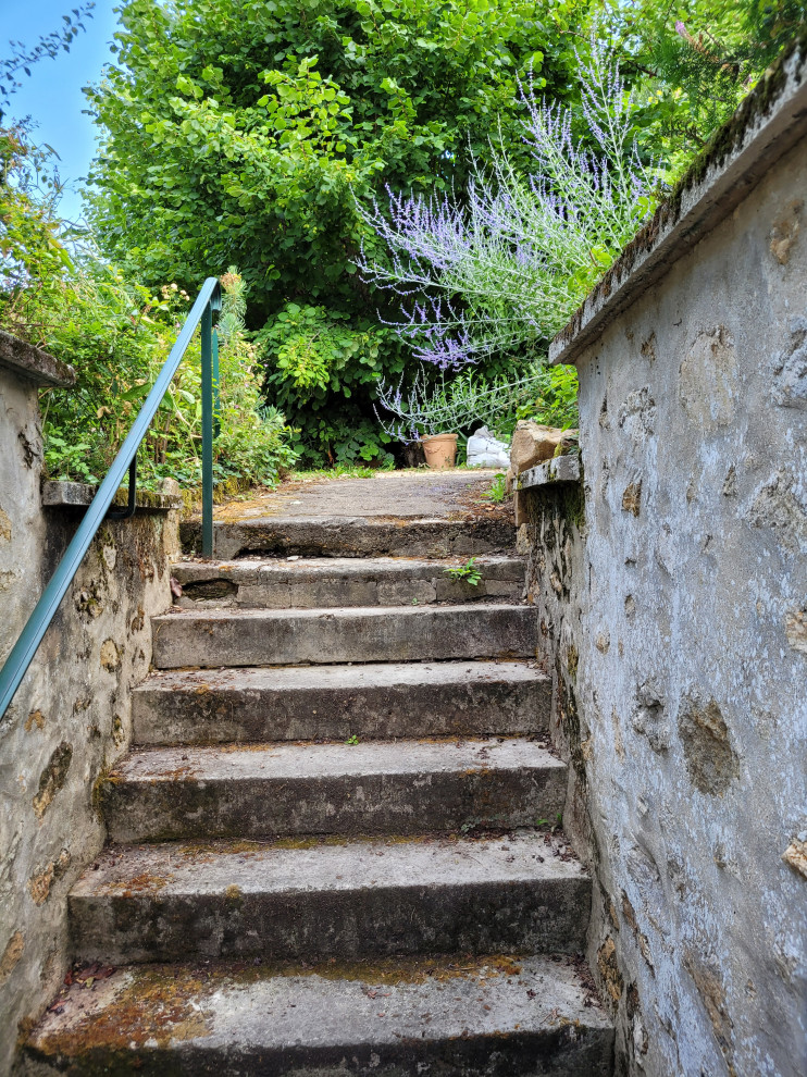 This is an example of an expansive country limestone staircase in Paris with travertine risers.