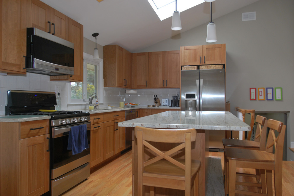 Large transitional l-shaped medium tone wood floor enclosed kitchen photo in Boston with an undermount sink, shaker cabinets, medium tone wood cabinets, granite countertops, white backsplash, ceramic backsplash, stainless steel appliances and an island