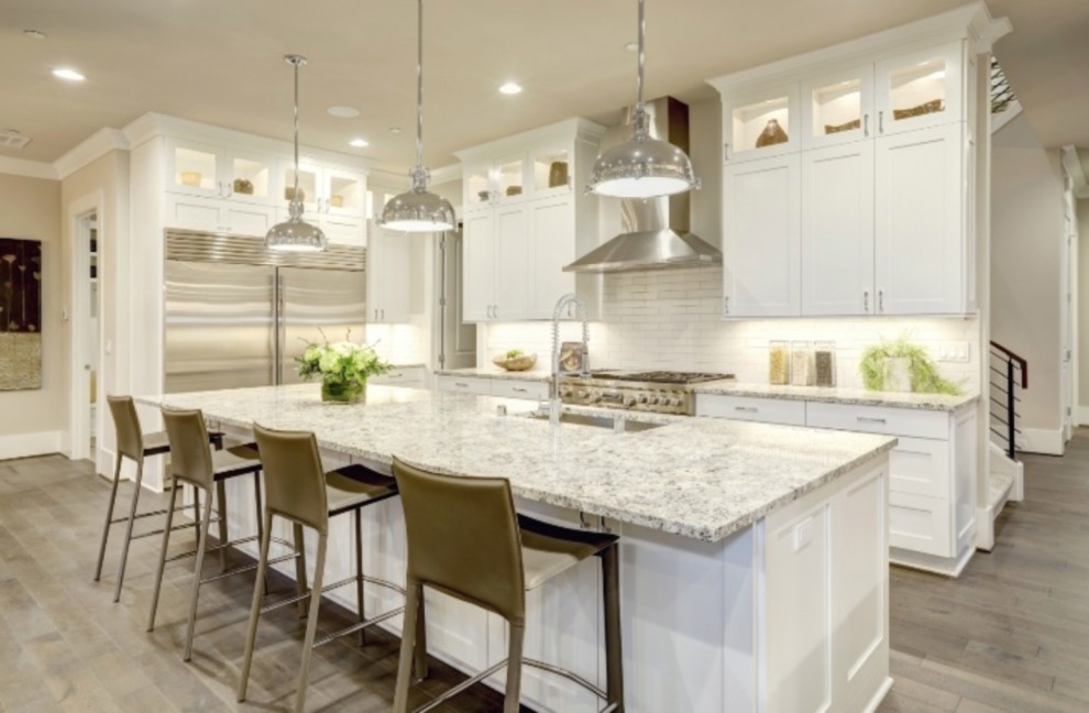 Modern inredning av ett stort flerfärgad flerfärgat kök, med en undermonterad diskho, skåp i shakerstil, vita skåp, granitbänkskiva, vitt stänkskydd, stänkskydd i tunnelbanekakel, rostfria vitvaror, mellanmörkt trägolv, en köksö och brunt golv