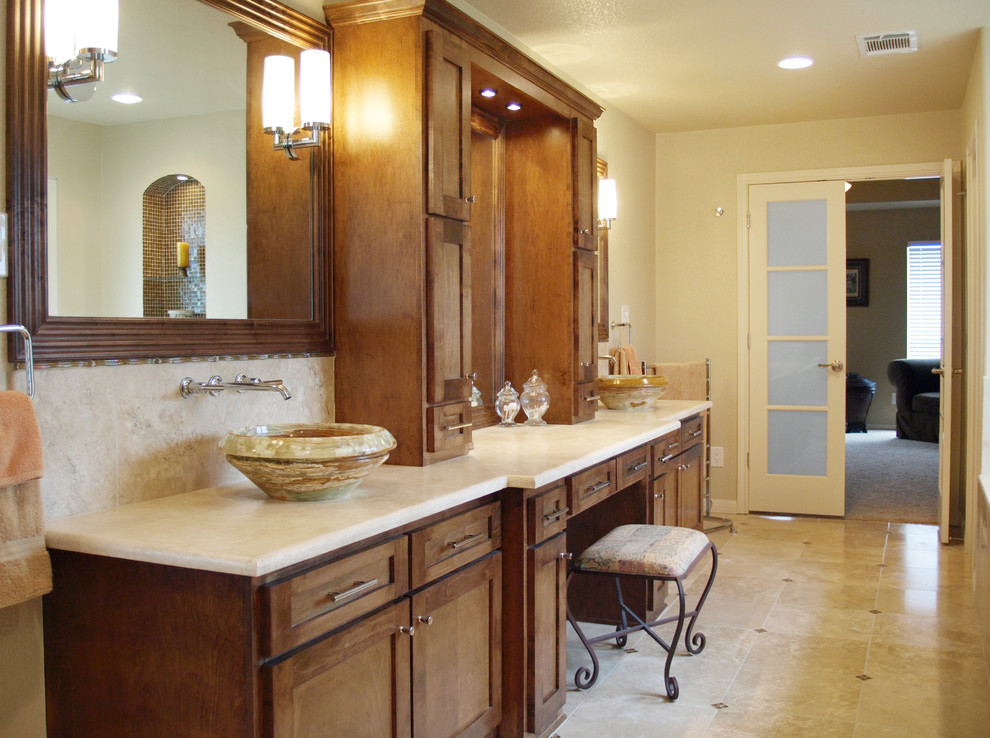 Large contemporary master bathroom in Austin with a vessel sink, shaker cabinets, beige walls, travertine floors, medium wood cabinets, a drop-in tub, multi-coloured tile, travertine and limestone benchtops.