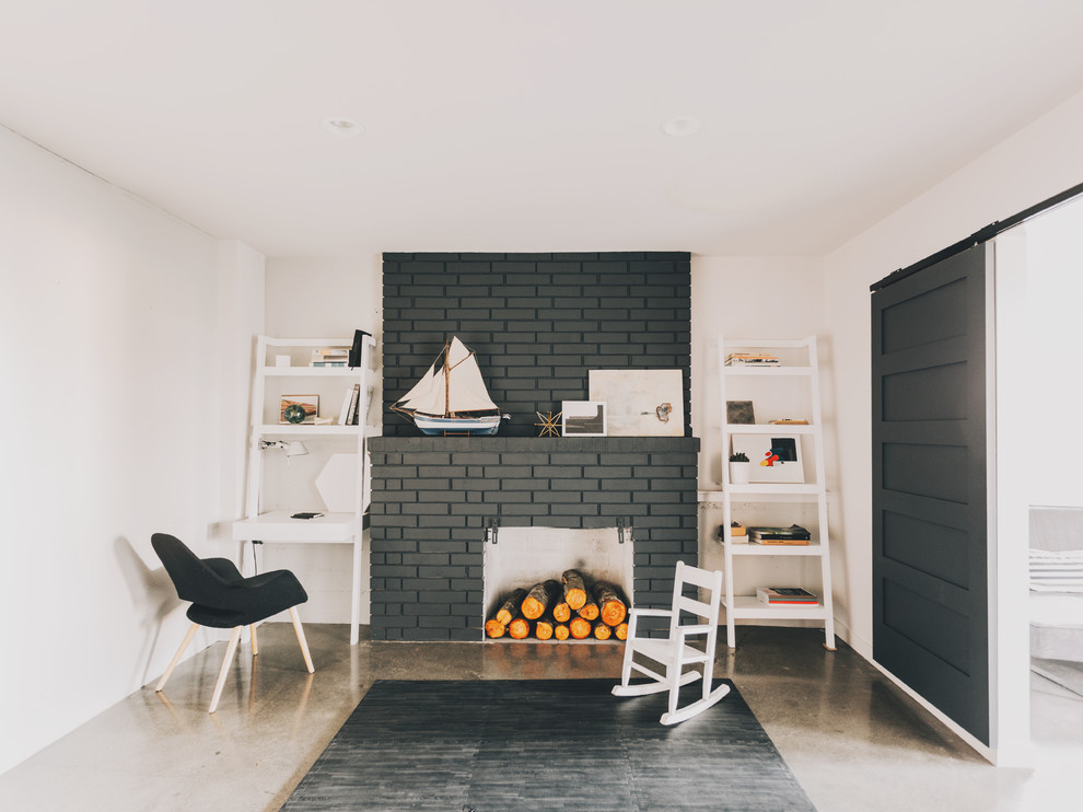 Photo of a mid-sized midcentury walk-out basement in Seattle with white walls, concrete floors, a standard fireplace and a brick fireplace surround.