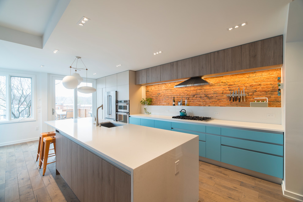 Inspiration for a contemporary kitchen in DC Metro with an undermount sink, flat-panel cabinets, blue cabinets, red splashback, brick splashback, light hardwood floors, with island and white benchtop.