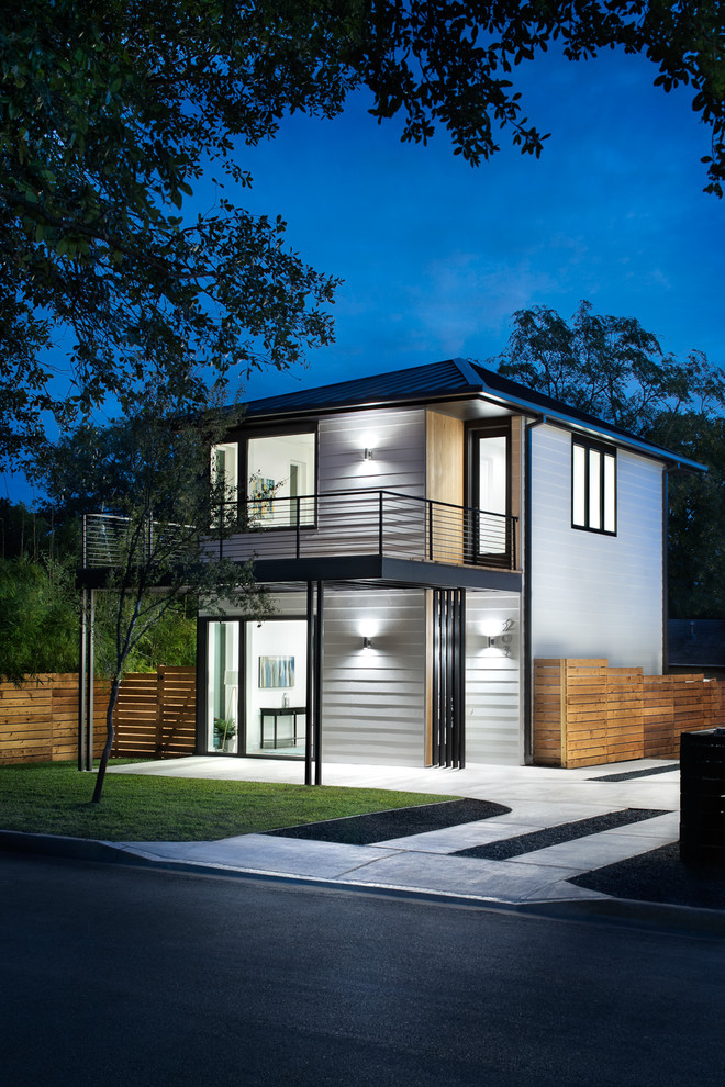 Large midcentury two-storey white house exterior in Austin with metal siding, a hip roof and a metal roof.