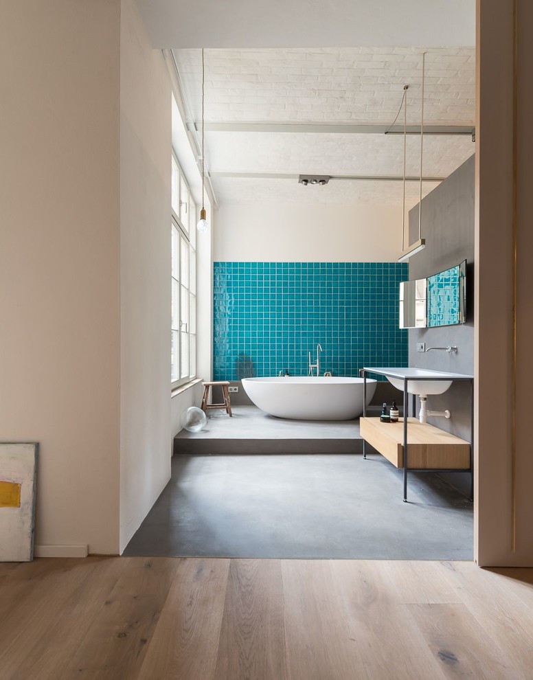 Photo of a mid-sized contemporary 3/4 bathroom in Berlin with a freestanding tub, a curbless shower, blue tile, ceramic tile, grey walls, concrete floors and a console sink.