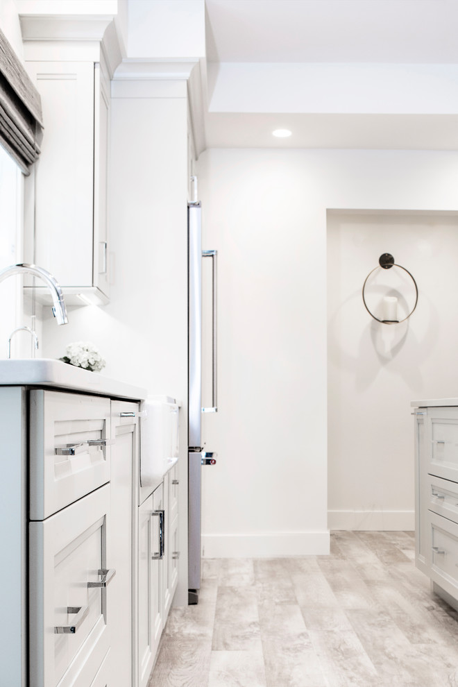 Mid-sized transitional single-wall vinyl floor and brown floor eat-in kitchen photo with quartzite countertops, white backsplash, stainless steel appliances, an island, shaker cabinets, an undermount sink, gray cabinets and porcelain backsplash