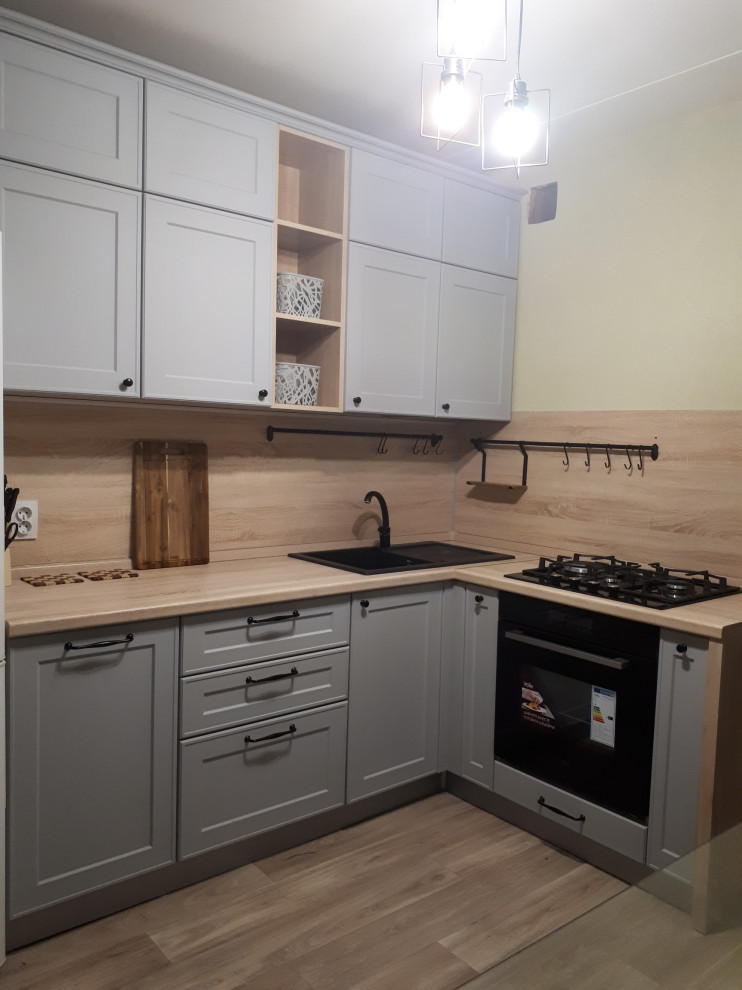 Medium sized traditional l-shaped kitchen/diner in Yekaterinburg with a submerged sink, grey cabinets, laminate countertops, black appliances, laminate floors and no island.