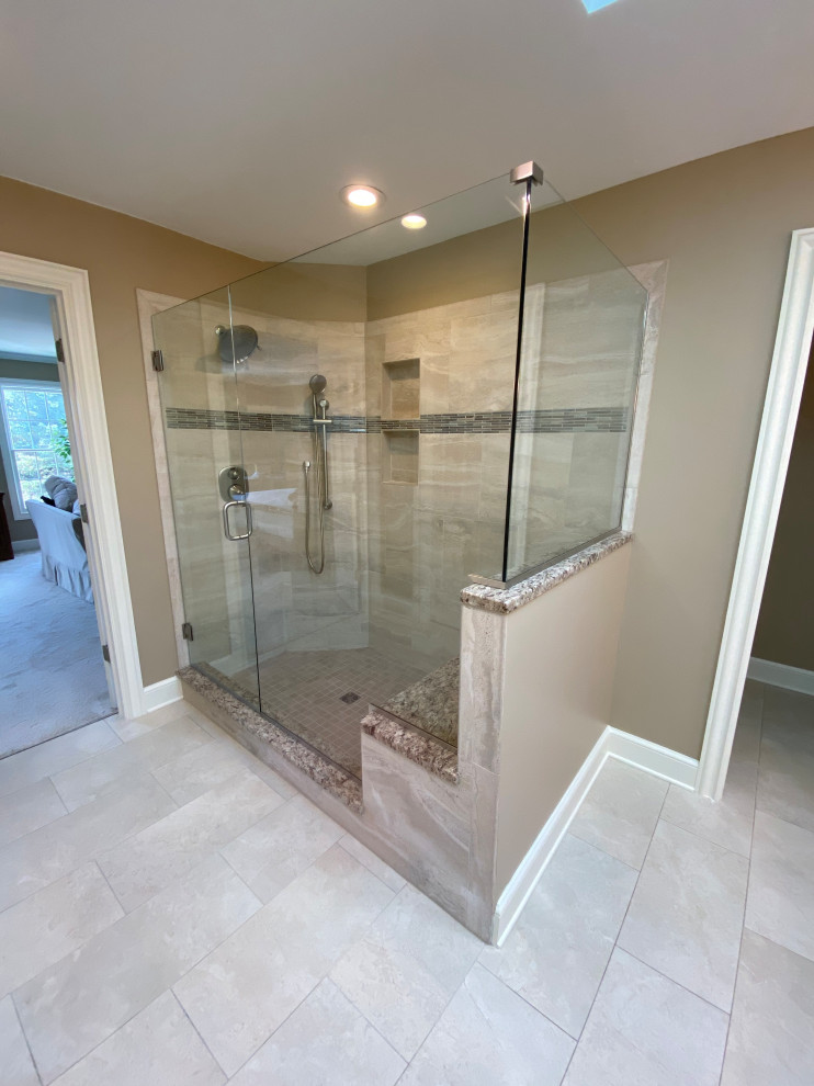 This is an example of a large traditional master bathroom in Cleveland with recessed-panel cabinets, white cabinets, a corner shower, a two-piece toilet, beige tile, porcelain tile, beige walls, porcelain floors, an undermount sink, granite benchtops, beige floor, a hinged shower door, brown benchtops, an enclosed toilet, a double vanity and a built-in vanity.