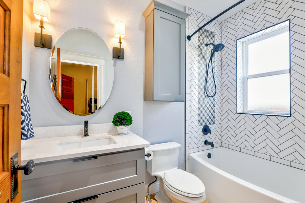 Design ideas for a mid-sized traditional bathroom in Other with shaker cabinets, grey cabinets, a drop-in tub, a shower/bathtub combo, white tile, grey walls, light hardwood floors, an undermount sink, quartzite benchtops, a shower curtain, white benchtops, a single vanity and a freestanding vanity.