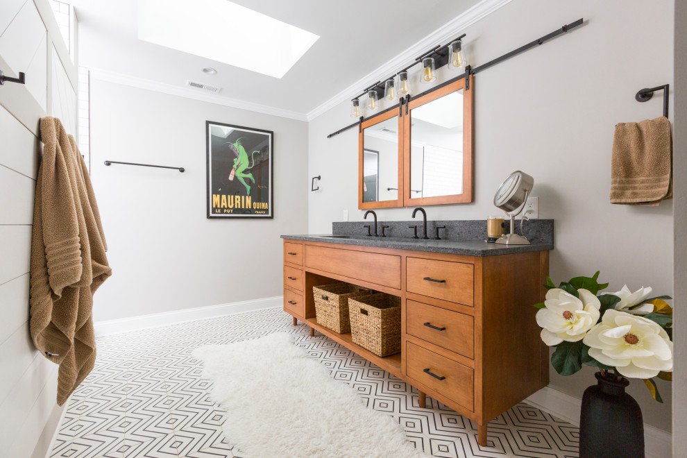 Photo of a mid-sized transitional master bathroom in Cincinnati with furniture-like cabinets, medium wood cabinets, a double shower, a wall-mount toilet, white tile, grey walls, cement tiles, a trough sink, granite benchtops, multi-coloured floor, an open shower, black benchtops, an enclosed toilet, a single vanity and a freestanding vanity.
