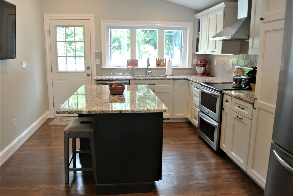 Transitional l-shaped medium tone wood floor and brown floor eat-in kitchen photo in Boston with an undermount sink, shaker cabinets, white cabinets, granite countertops, beige backsplash, subway tile backsplash, stainless steel appliances, an island and beige countertops
