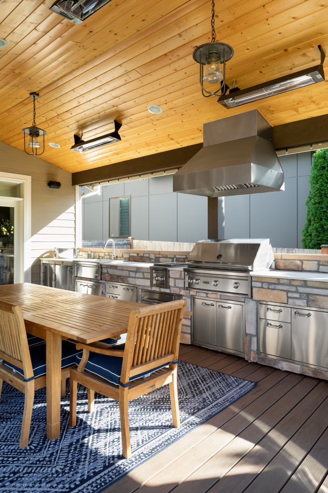 Design ideas for a large contemporary backyard and ground level deck in Seattle with an outdoor kitchen, a roof extension and cable railing.