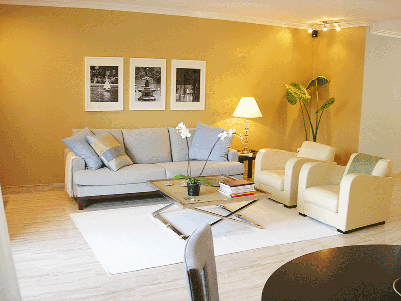 Imagen de salón abierto actual con paredes amarillas, televisor en una esquina y suelo multicolor