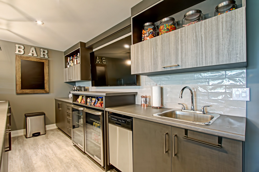 Photo of a mid-sized transitional galley seated home bar in Toronto with a drop-in sink, flat-panel cabinets, grey cabinets, concrete benchtops, white splashback, glass tile splashback, medium hardwood floors, beige floor and beige benchtop.
