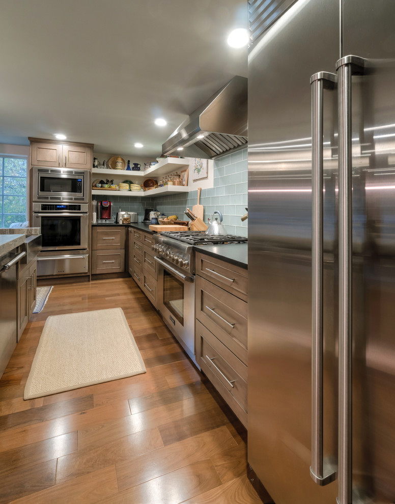 Large arts and crafts l-shaped eat-in kitchen in Boston with an integrated sink, recessed-panel cabinets, grey cabinets, granite benchtops, blue splashback, ceramic splashback, stainless steel appliances, light hardwood floors, with island and brown floor.