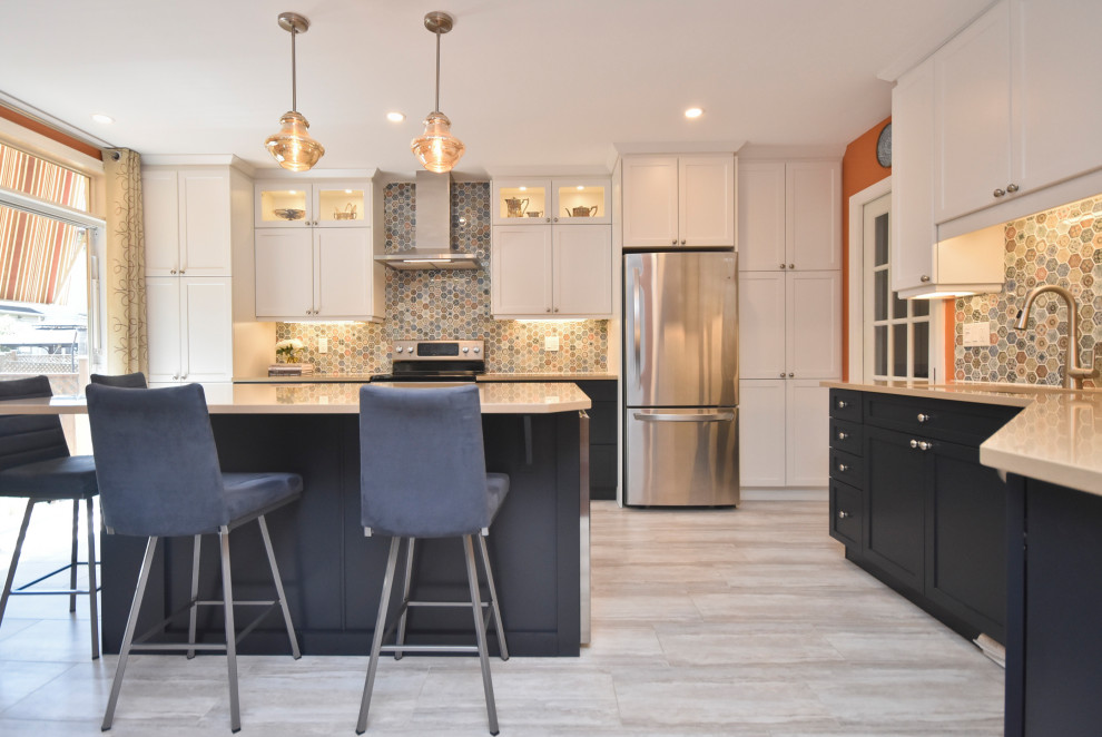 Example of a mid-sized transitional l-shaped vinyl floor and beige floor kitchen design in Ottawa with a double-bowl sink, shaker cabinets, white cabinets, quartzite countertops, multicolored backsplash, mosaic tile backsplash, stainless steel appliances, an island and beige countertops