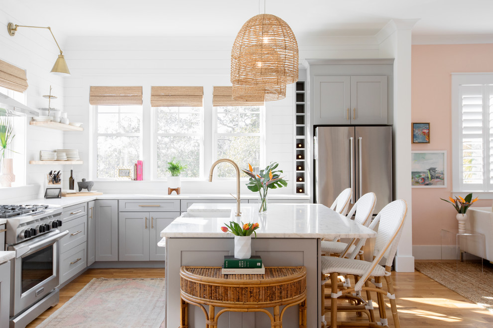 Beach style u-shaped kitchen in Charleston with a farmhouse sink, shaker cabinets, grey cabinets, white splashback, stainless steel appliances, medium hardwood floors, with island, brown floor and white benchtop.