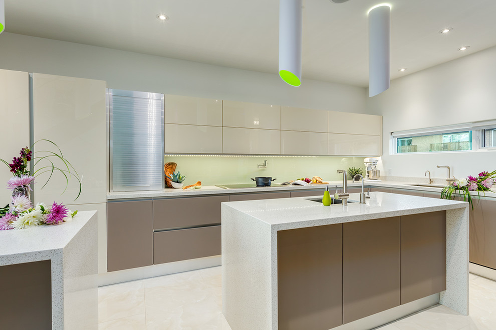 Inspiration for an expansive transitional l-shaped open plan kitchen in Calgary with an undermount sink, flat-panel cabinets, beige cabinets, quartz benchtops, green splashback, glass sheet splashback, porcelain floors and multiple islands.