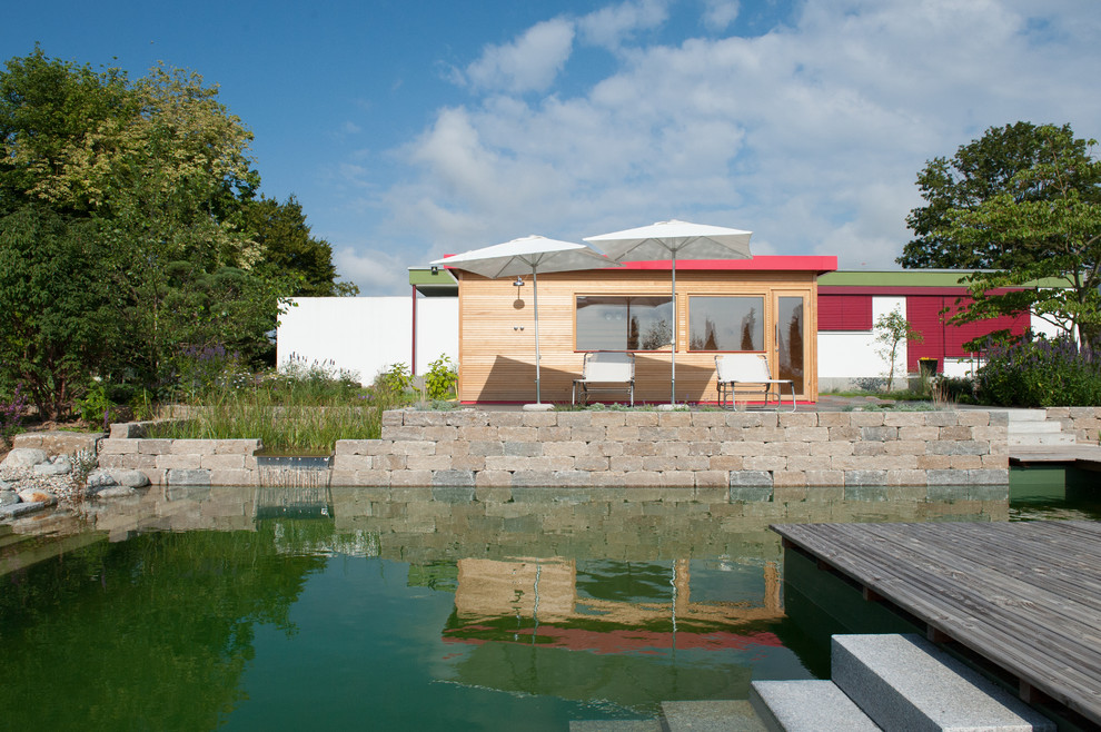 Design ideas for an expansive traditional l-shaped natural pool in Stuttgart with a pool house and natural stone pavers.
