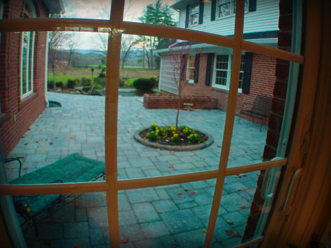 Example of a large mountain style backyard concrete paver patio kitchen design with no cover