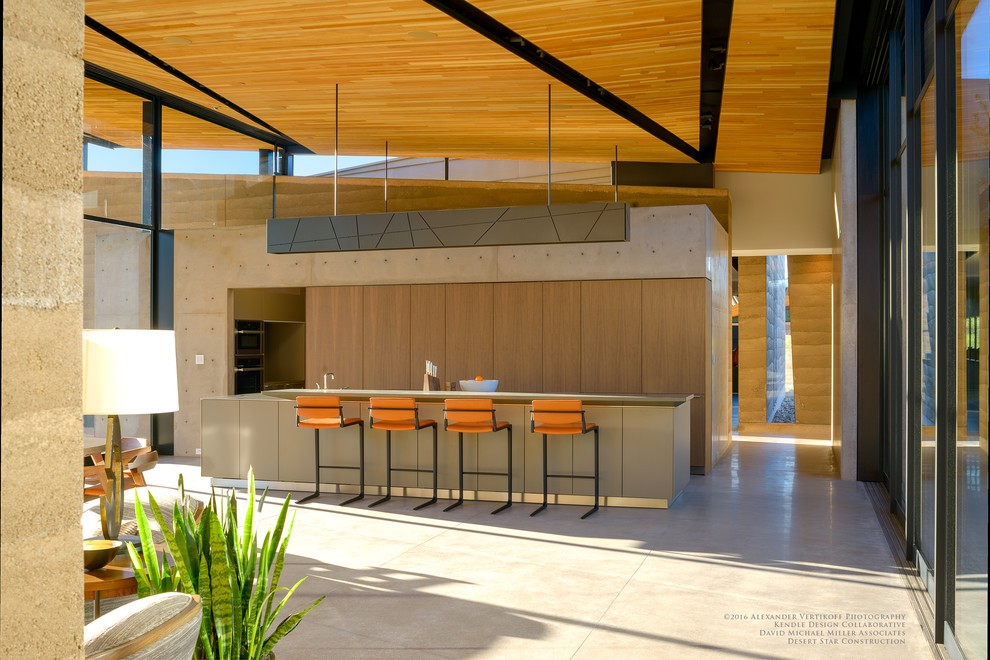 Example of a mid-sized minimalist galley concrete floor and gray floor home design design in Phoenix with flat-panel cabinets, medium tone wood cabinets, stainless steel countertops and an island