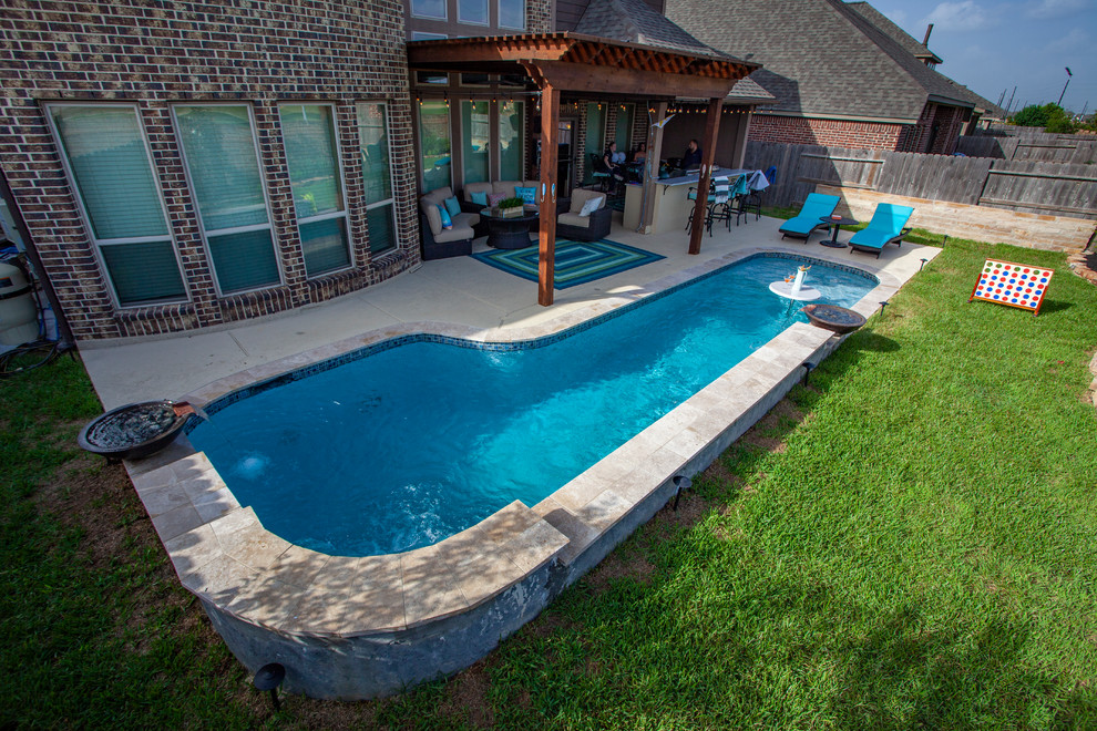 Photo of a small tropical backyard l-shaped natural pool in Houston with a water feature and tile.