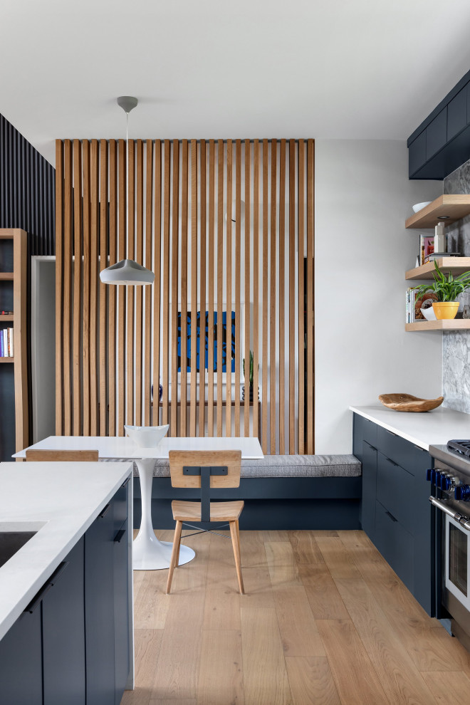Inspiration for a large midcentury galley eat-in kitchen in Austin with an undermount sink, flat-panel cabinets, blue cabinets, quartz benchtops, grey splashback, marble splashback, stainless steel appliances, light hardwood floors, a peninsula and white benchtop.