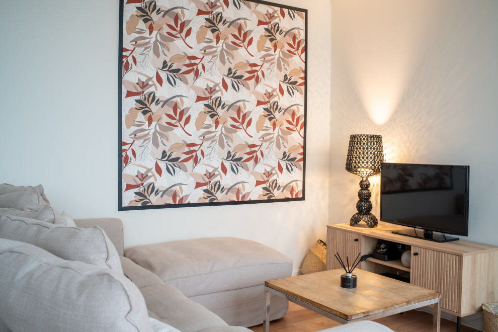 На фото: открытая гостиная комната среднего размера в стиле неоклассика (современная классика) с белыми стенами, светлым паркетным полом, отдельно стоящим телевизором, коричневым полом и обоями на стенах без камина
