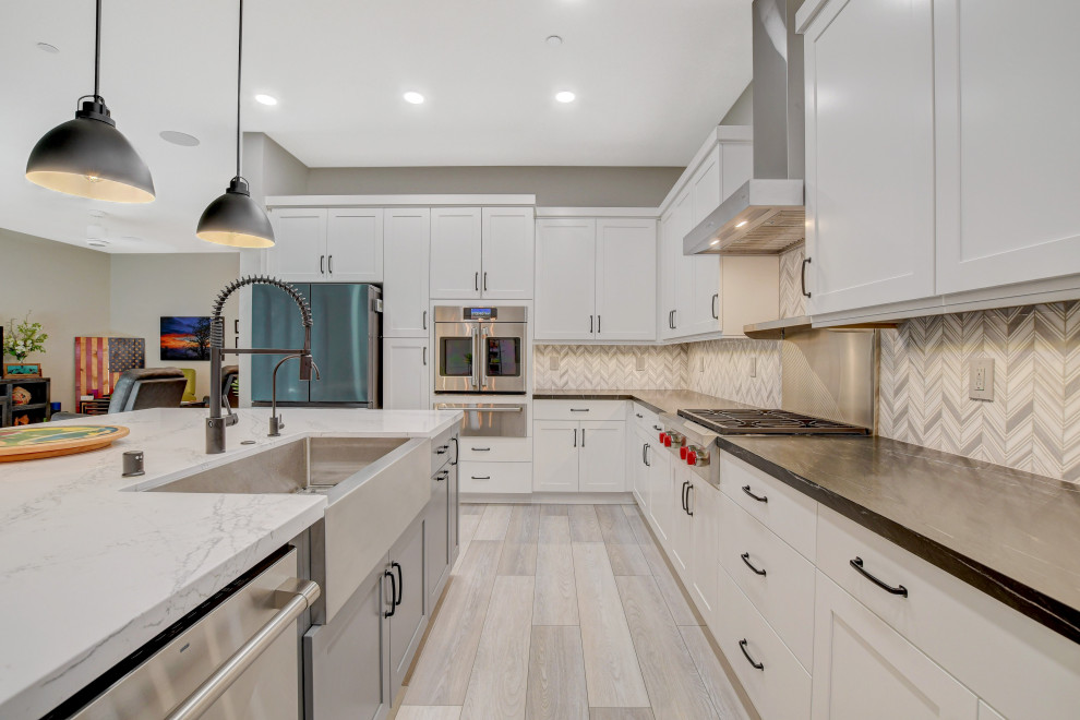 Photo of a contemporary kitchen in Las Vegas with a double-bowl sink, white cabinets, quartz worktops, grey splashback, limestone splashback, stainless steel appliances, an island and white worktops.