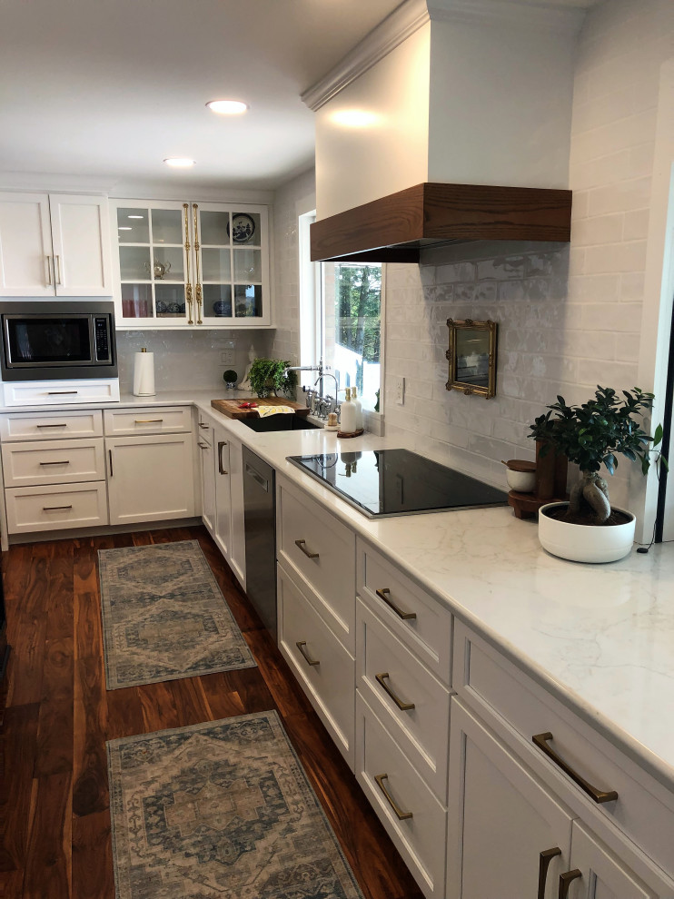 Example of a mid-sized transitional l-shaped medium tone wood floor and brown floor kitchen pantry design with an undermount sink, flat-panel cabinets, blue cabinets, quartz countertops, white backsplash, subway tile backsplash, stainless steel appliances, an island and gray countertops
