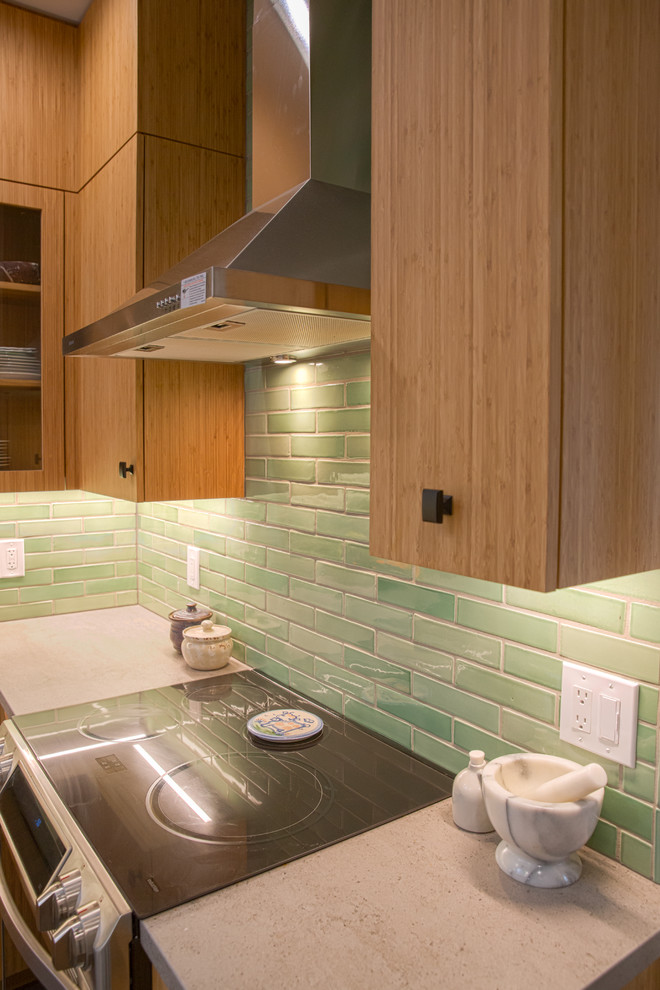 Photo of a contemporary u-shaped separate kitchen in San Francisco with an undermount sink, flat-panel cabinets, medium wood cabinets, solid surface benchtops, green splashback, subway tile splashback, stainless steel appliances, ceramic floors, with island, grey floor and grey benchtop.