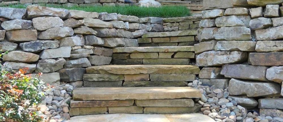 This is an example of a mid-sized partial sun front yard retaining wall landscape.
