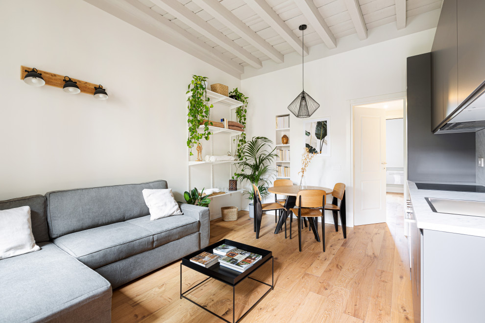 Photo of a small scandinavian open concept living room in Milan with white walls, light hardwood floors, no fireplace, a wall-mounted tv, brown floor and wood.