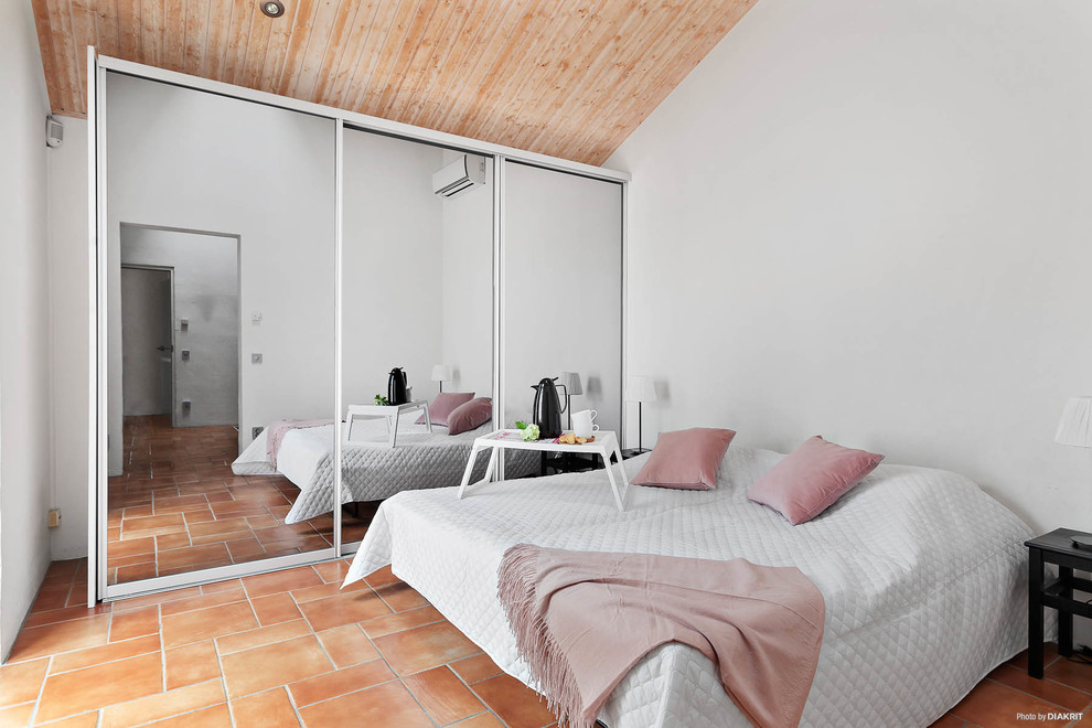 Photo of a contemporary bedroom in Malmo with white walls and terra-cotta floors.