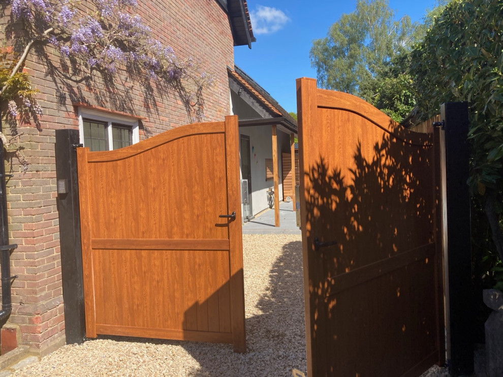 This is an example of a medium sized contemporary side driveway full sun garden for summer in Buckinghamshire with a gate, gravel and a wood fence.