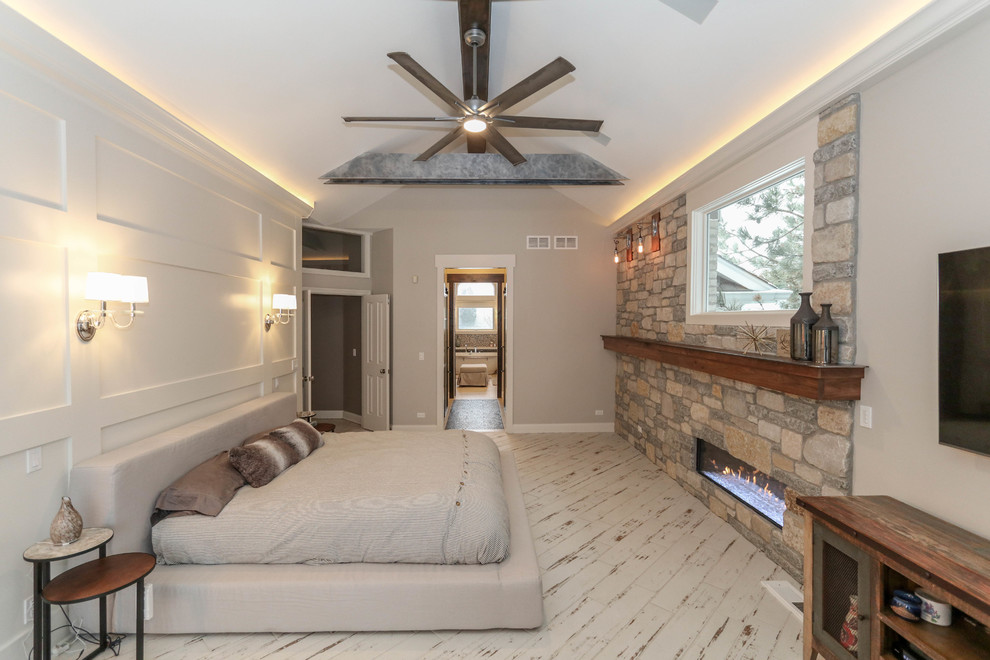 This is an example of an industrial master bedroom in Chicago with beige walls, ceramic floors, a standard fireplace, a stone fireplace surround and beige floor.