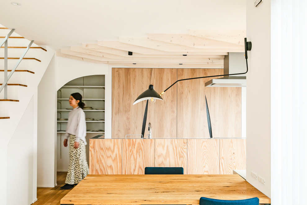 Cette photo montre une cuisine ouverte linéaire tendance avec un plan de travail en surface solide, un sol en bois brun, îlot et poutres apparentes.
