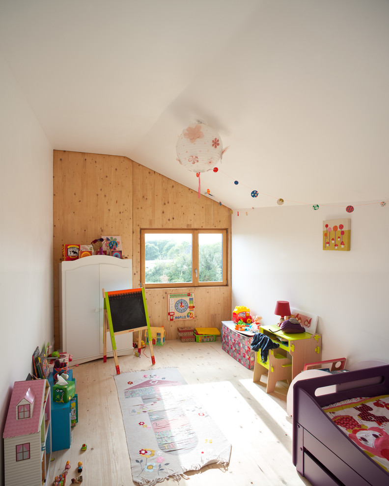 This is an example of a contemporary kids' room for girls in Nantes with white walls and light hardwood floors.