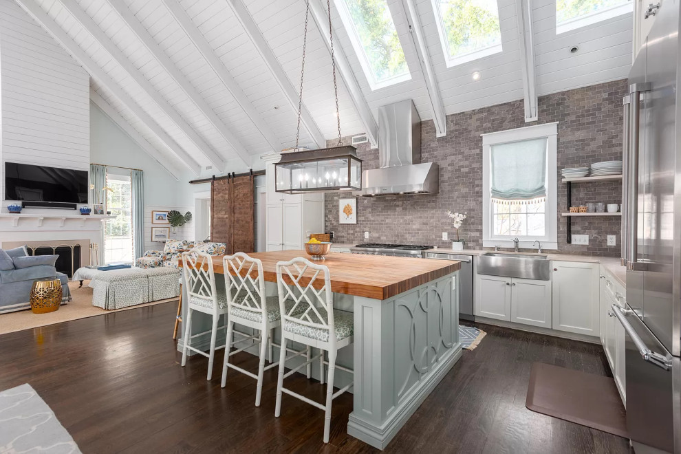 Traditional l-shaped open plan kitchen in Charleston with a farmhouse sink, shaker cabinets, white cabinets, grey splashback, stainless steel appliances, dark hardwood floors, with island, brown floor, beige benchtop, exposed beam, timber and vaulted.