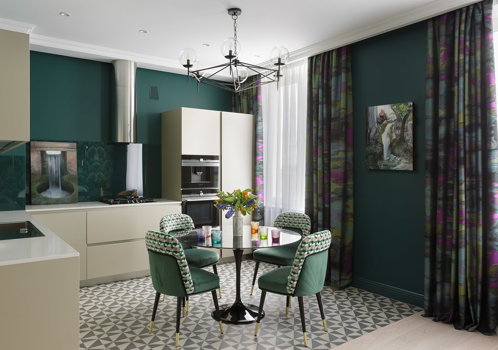 This is an example of a contemporary l-shaped eat-in kitchen in Saint Petersburg with flat-panel cabinets, beige cabinets, green splashback, black appliances, multi-coloured floor and white benchtop.