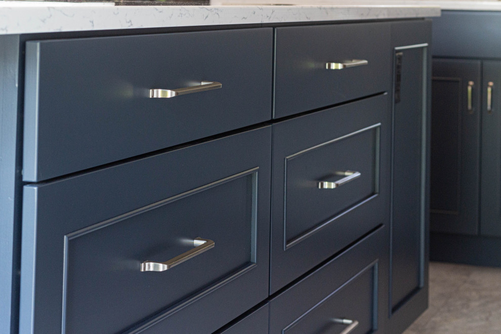 Example of a mid-sized transitional l-shaped porcelain tile and gray floor eat-in kitchen design with an undermount sink, flat-panel cabinets, white cabinets, quartz countertops, white backsplash, subway tile backsplash, stainless steel appliances, an island and white countertops
