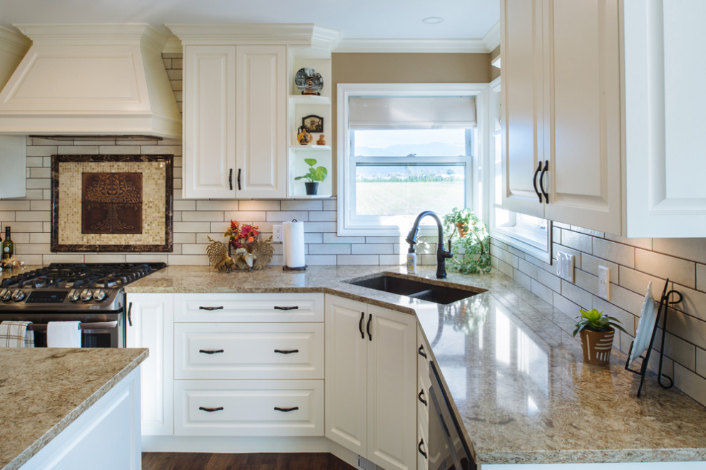 This is an example of a large u-shaped kitchen/diner in Vancouver with a submerged sink, raised-panel cabinets, white cabinets, engineered stone countertops, white splashback, metro tiled splashback, stainless steel appliances, vinyl flooring, an island, brown floors and beige worktops.