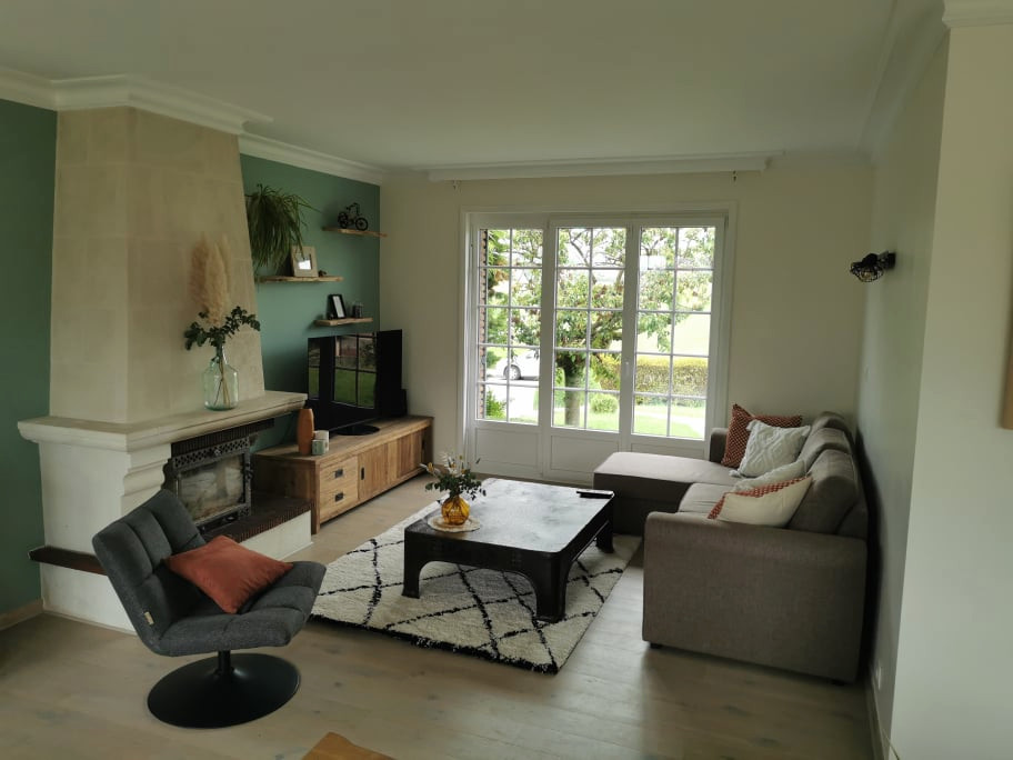 Cette photo montre un salon tendance de taille moyenne et ouvert avec un mur beige, parquet clair, une cheminée standard, un manteau de cheminée en pierre et un téléviseur indépendant.