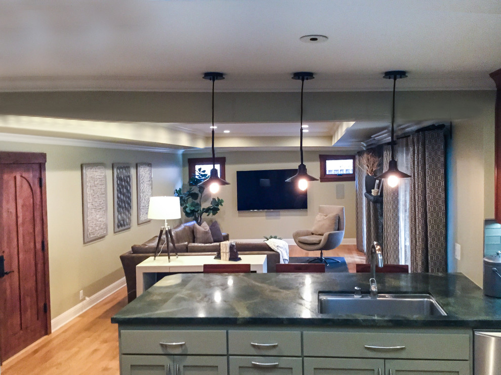 Example of a mid-sized transitional u-shaped medium tone wood floor kitchen design with an undermount sink, shaker cabinets, medium tone wood cabinets, granite countertops, blue backsplash, glass tile backsplash, stainless steel appliances and an island
