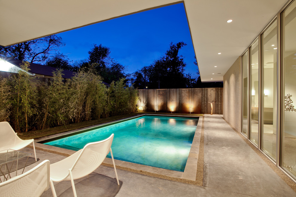 This is an example of a mid-sized modern rectangular pool in Dallas with concrete slab.