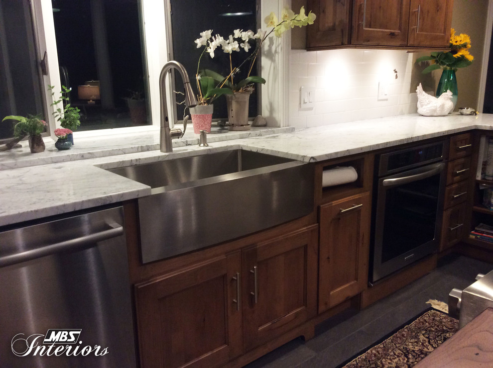 Eat-in kitchen - mid-sized transitional u-shaped ceramic tile and gray floor eat-in kitchen idea with a farmhouse sink, recessed-panel cabinets, medium tone wood cabinets, marble countertops, white backsplash, subway tile backsplash, stainless steel appliances and an island