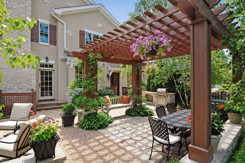 Photo of a large traditional backyard patio in Chicago with natural stone pavers and a pergola.