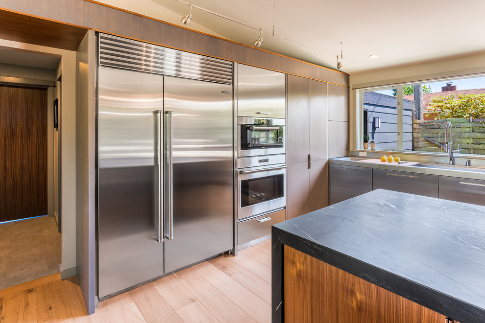 This is an example of a midcentury kitchen in Seattle with flat-panel cabinets and soapstone benchtops.