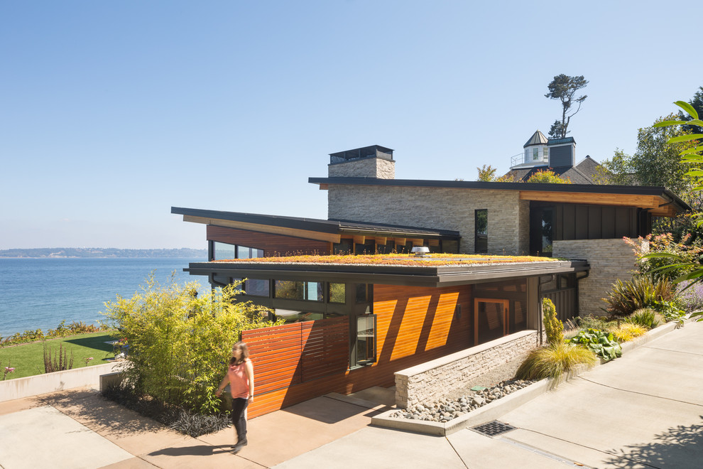 Inspiration for a mid-sized contemporary two-storey brown house exterior in Seattle with stone veneer, a shed roof and a green roof.